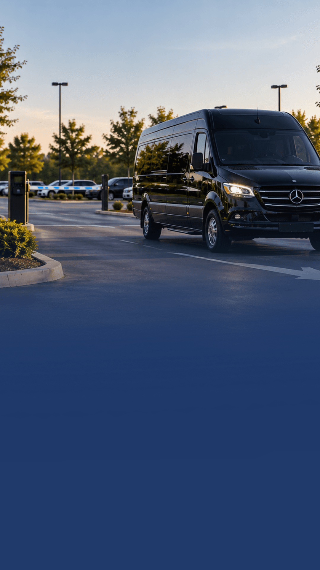 A black passenger shuttle van waiting near a parking lot entrance.